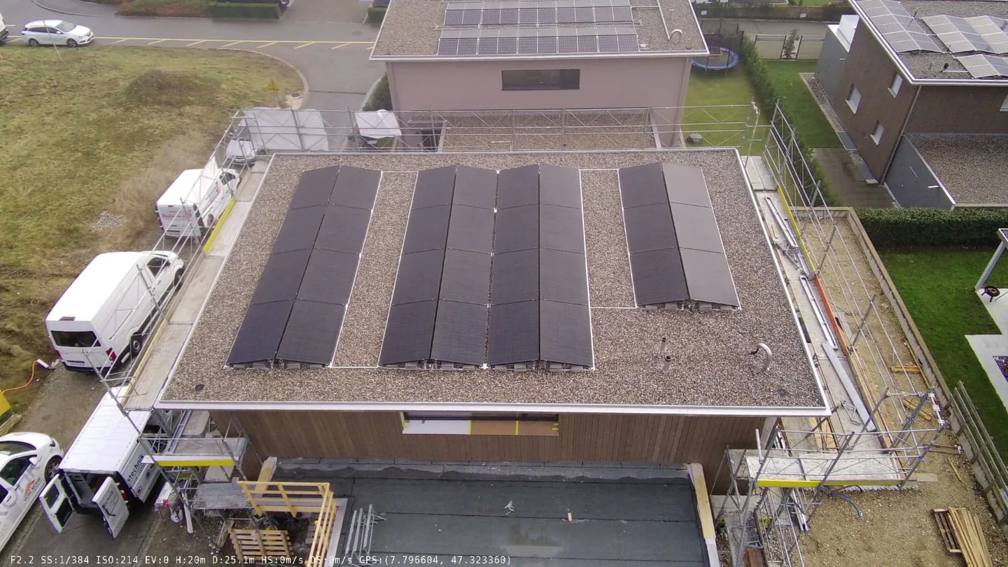 Luftaufnahme einer Photovoltaikanlage mit mehreren Modulreihen auf einem Flachdach